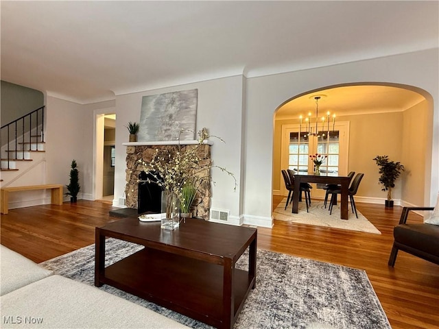 living area featuring visible vents, arched walkways, wood finished floors, stairway, and a chandelier