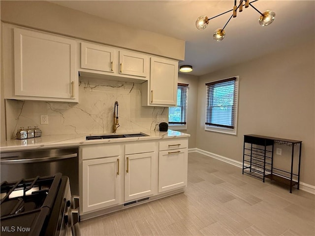 kitchen with white cabinets, a notable chandelier, a sink, backsplash, and visible vents