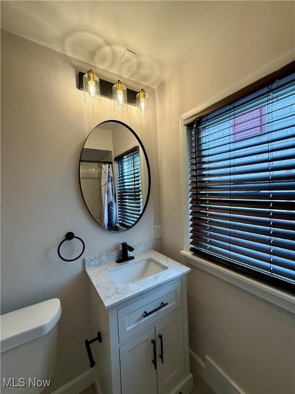full bathroom featuring baseboards, toilet, and vanity