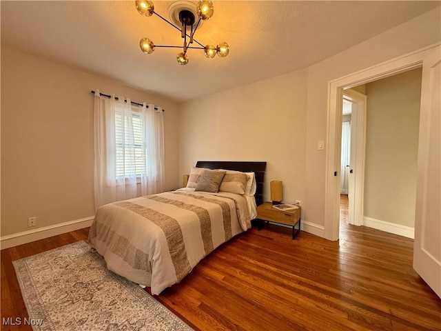 bedroom featuring baseboards, an inviting chandelier, and dark wood finished floors