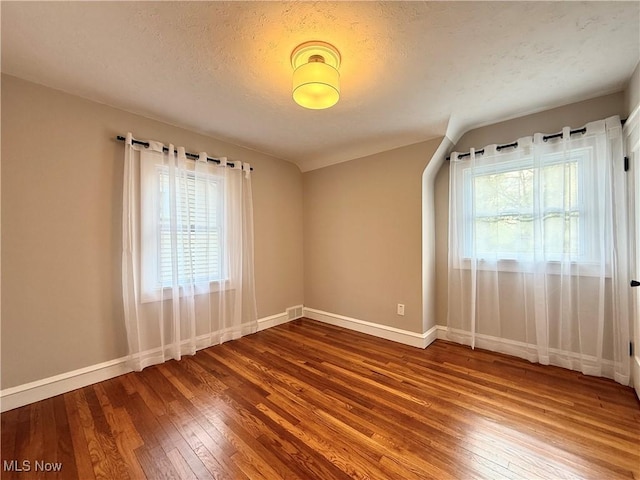 empty room featuring a healthy amount of sunlight, baseboards, and hardwood / wood-style floors