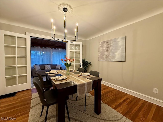 dining space featuring baseboards, a notable chandelier, and wood finished floors