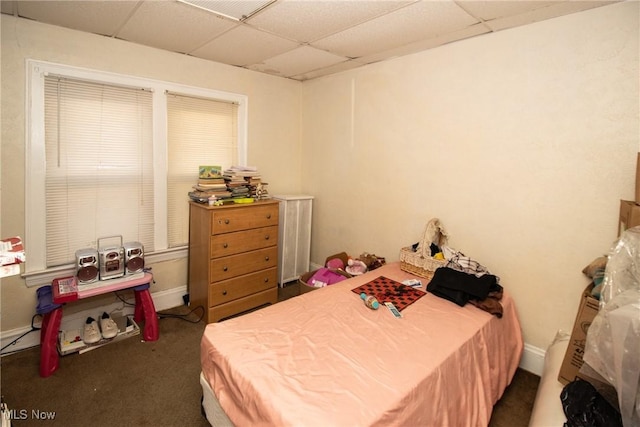 carpeted bedroom with baseboards and a drop ceiling
