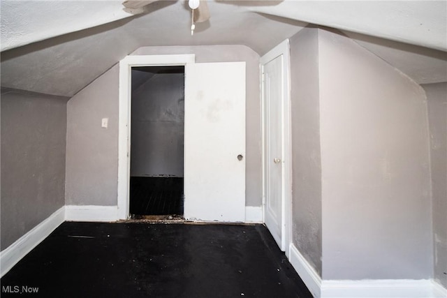 additional living space with baseboards, ceiling fan, and vaulted ceiling