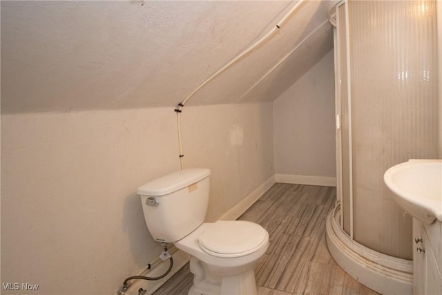 bathroom featuring wood finished floors, lofted ceiling, toilet, a textured ceiling, and a shower stall