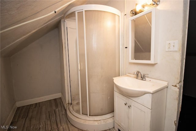 bathroom with vanity, a shower stall, wood finished floors, and lofted ceiling