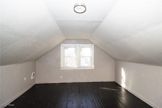 additional living space featuring baseboards, visible vents, hardwood / wood-style flooring, and lofted ceiling