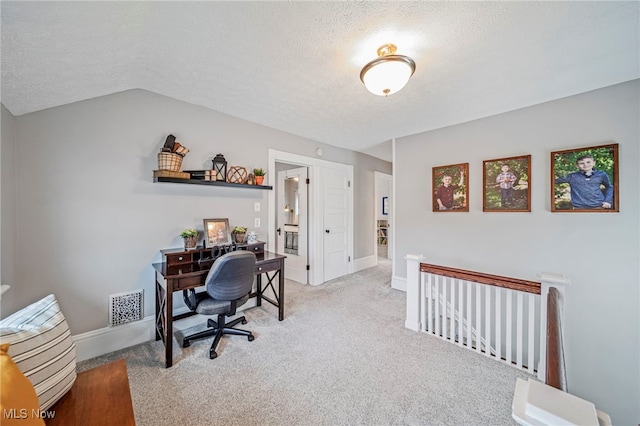 office space featuring carpet flooring, a textured ceiling, visible vents, and vaulted ceiling
