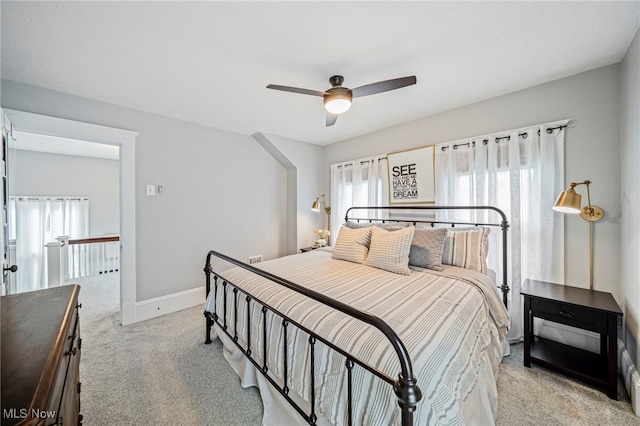 bedroom with light colored carpet, a ceiling fan, and baseboards