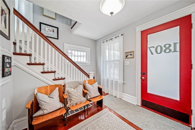 entrance foyer with baseboards, stairs, and wood finished floors