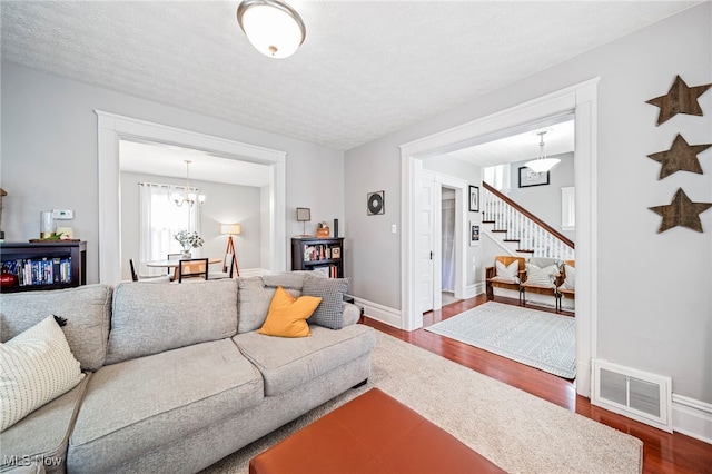 living area with visible vents, stairs, baseboards, dark wood-style floors, and a chandelier