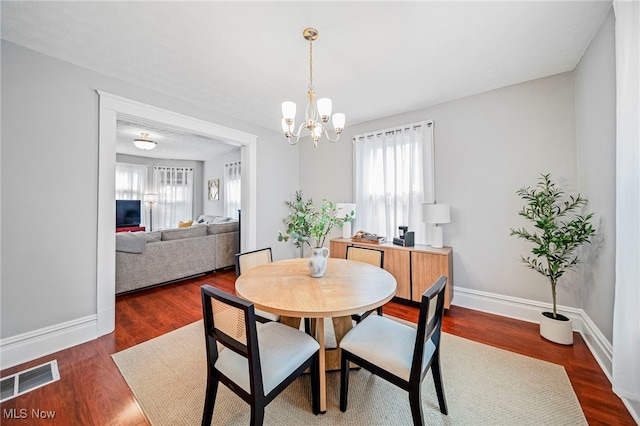 dining space featuring baseboards, a notable chandelier, a healthy amount of sunlight, and visible vents