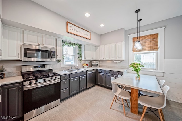 kitchen with a sink, light countertops, stainless steel appliances, white cabinetry, and gray cabinetry