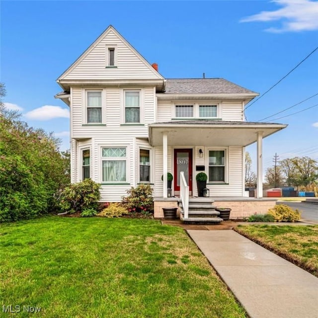 view of front of home with a front lawn, covered porch, and a chimney