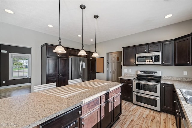 kitchen with pendant lighting, appliances with stainless steel finishes, dark brown cabinets, recessed lighting, and light wood-style flooring