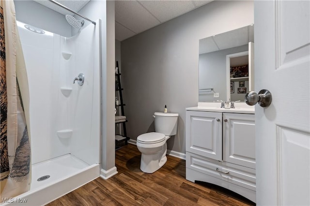 bathroom featuring a shower stall, wood finished floors, vanity, baseboards, and toilet