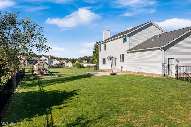 rear view of house with a chimney, a lawn, a patio area, a fenced backyard, and a playground