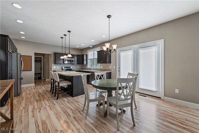 dining area featuring recessed lighting, baseboards, an inviting chandelier, and light wood-style flooring