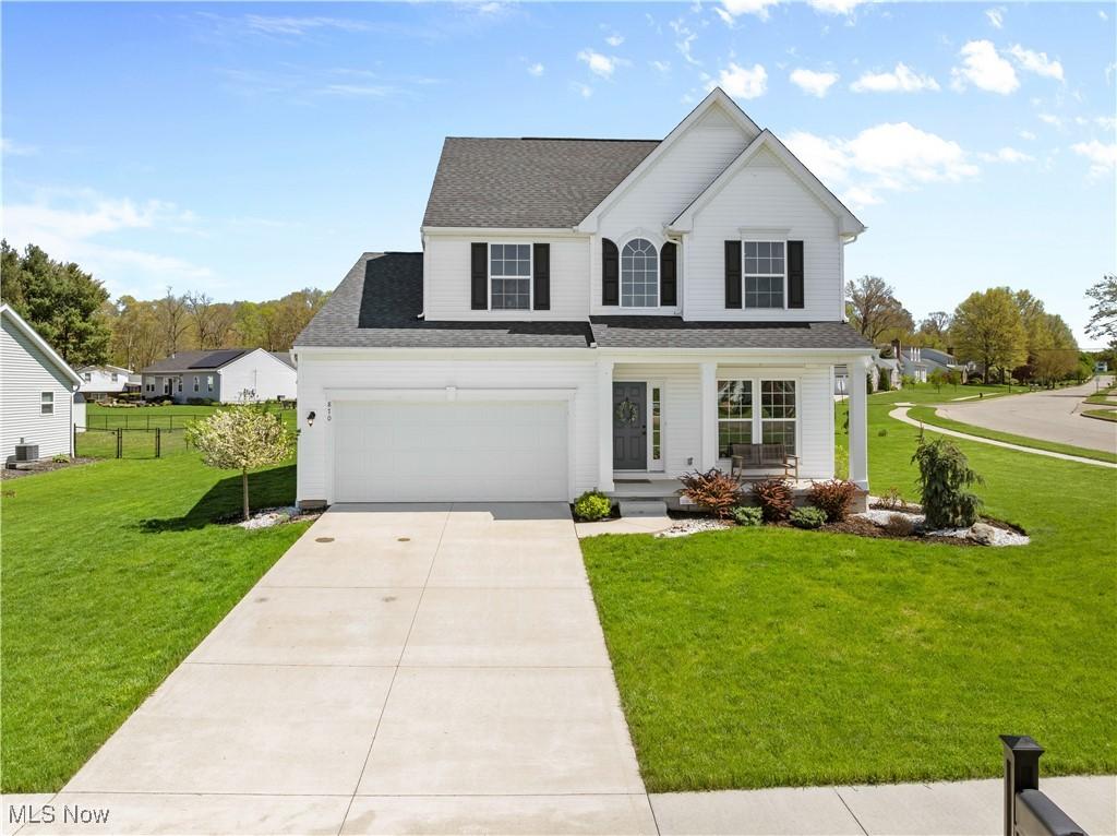 870 Thewes Cir, Louisville, OH 44641 - traditional-style house with a front lawn, covered porch, roof with shingles, concrete driveway, and an attached garage