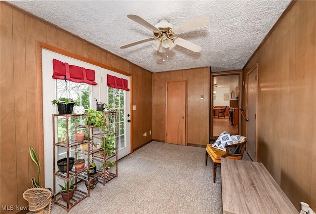 entryway featuring wooden walls, ceiling fan, carpet flooring, and a textured ceiling