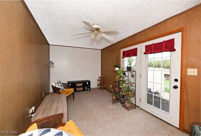 interior space with wooden walls, carpet floors, ceiling fan, and a textured ceiling