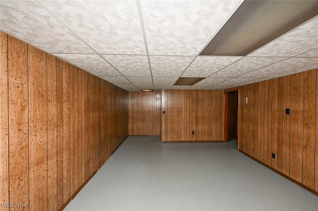 finished below grade area featuring wood walls and a drop ceiling