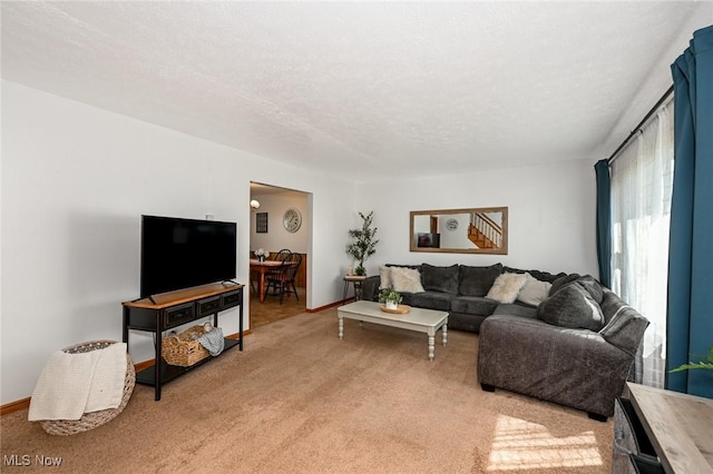 living room featuring baseboards, light carpet, and a textured ceiling