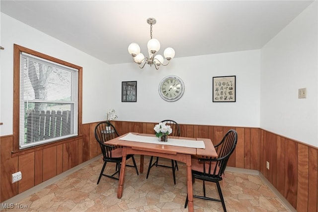 dining area with a notable chandelier, wood walls, and wainscoting