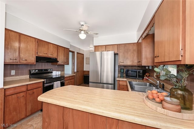 kitchen featuring a sink, stainless steel appliances, a peninsula, tasteful backsplash, and under cabinet range hood