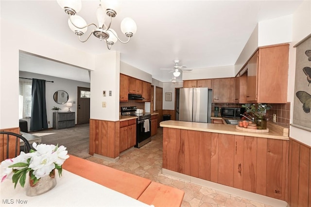 kitchen featuring brown cabinetry, range with electric stovetop, freestanding refrigerator, a peninsula, and under cabinet range hood