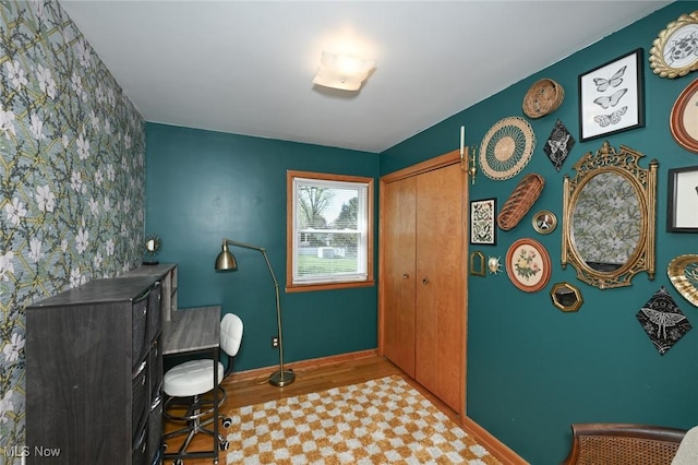 office featuring baseboards and an accent wall
