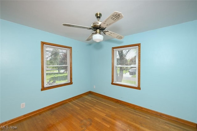 unfurnished room with baseboards, a healthy amount of sunlight, and wood finished floors