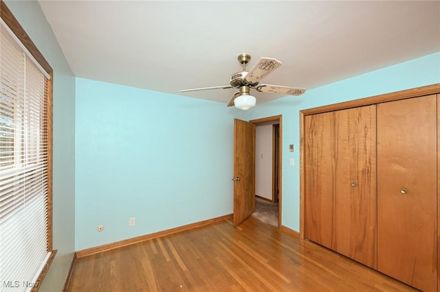 unfurnished bedroom with a closet, a ceiling fan, light wood-style flooring, and baseboards