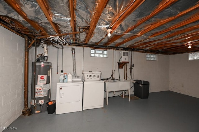 below grade area featuring water heater, plenty of natural light, washing machine and dryer, and a sink