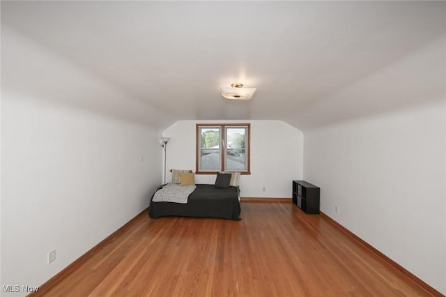 bedroom with baseboards, wood finished floors, and vaulted ceiling
