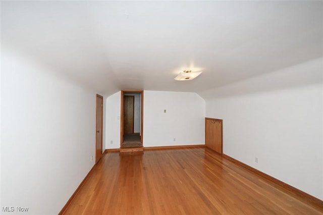 additional living space with baseboards, light wood-style flooring, and lofted ceiling