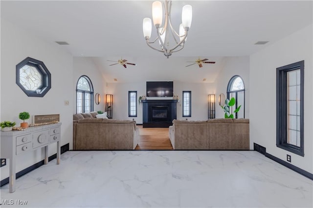 living room featuring a glass covered fireplace, ceiling fan with notable chandelier, marble finish floor, and lofted ceiling