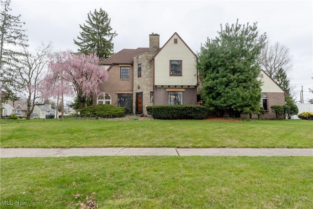 view of front of house featuring a chimney, stone siding, and a front lawn