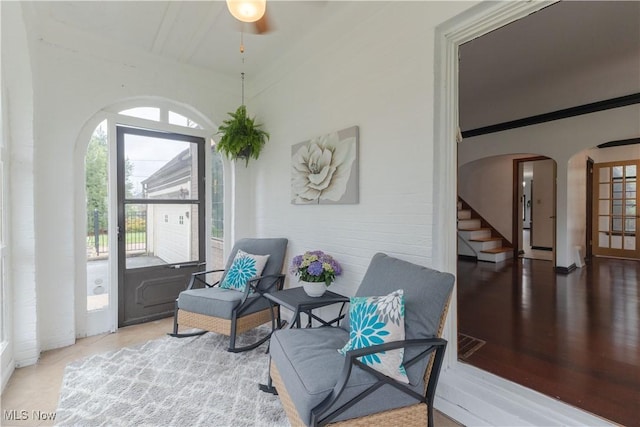 living area featuring plenty of natural light, arched walkways, stairs, and ceiling fan