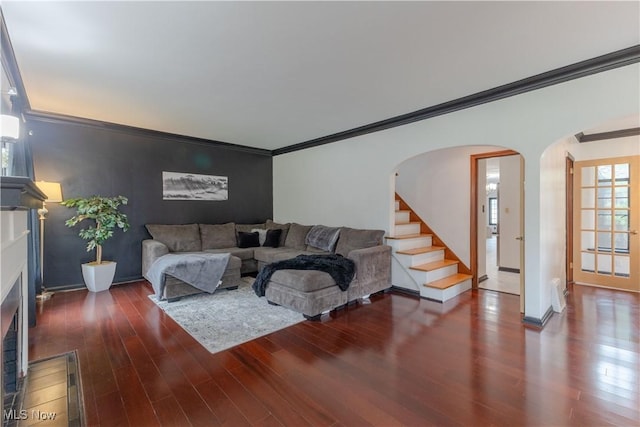 living area featuring arched walkways, ornamental molding, wood finished floors, and an accent wall