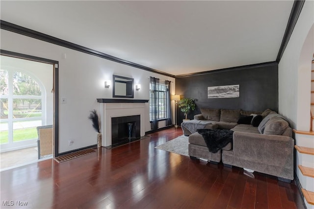 living area with crown molding, a fireplace with flush hearth, and wood finished floors