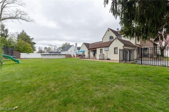 rear view of house featuring a yard, a fenced in pool, a fenced backyard, and a patio area