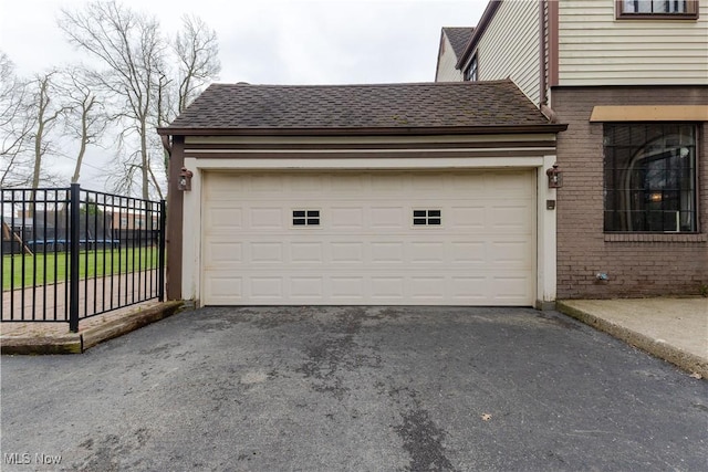 garage with fence and aphalt driveway