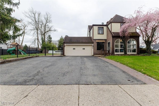 view of front of house with aphalt driveway, roof with shingles, a garage, fence, and a front lawn