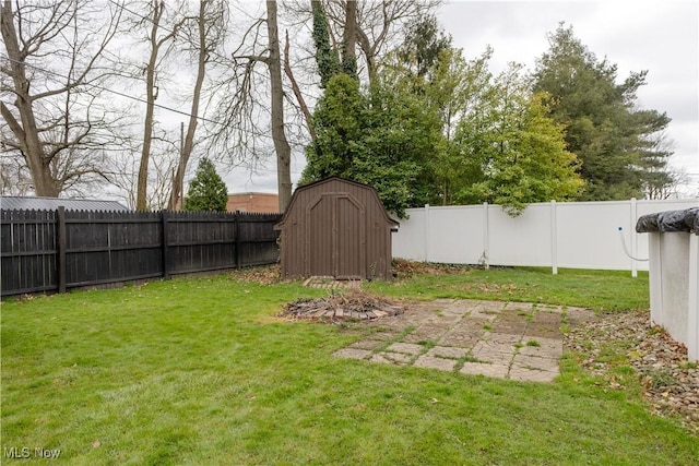 view of yard with a storage unit, a fenced backyard, a patio area, and an outbuilding