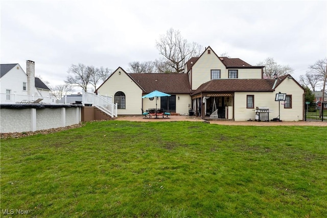 rear view of property featuring fence, a patio, and a yard