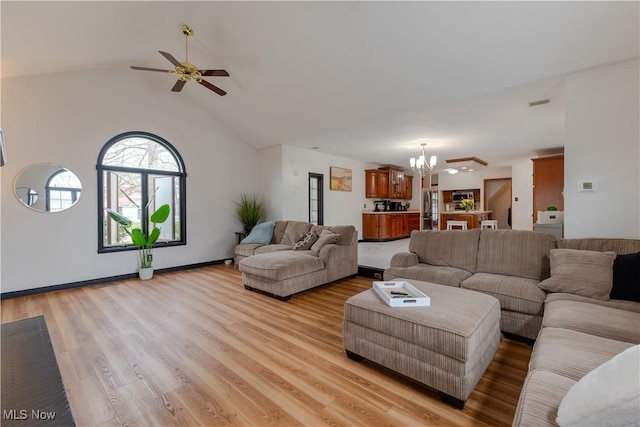 living room featuring baseboards, ceiling fan with notable chandelier, light wood-style flooring, and lofted ceiling