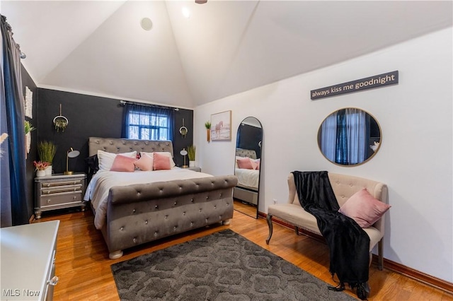 bedroom with high vaulted ceiling, baseboards, and wood finished floors