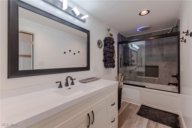 bathroom with recessed lighting, combined bath / shower with glass door, wood finished floors, and vanity