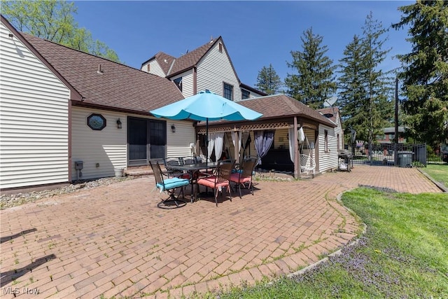 rear view of property featuring fence, a shingled roof, and a patio area